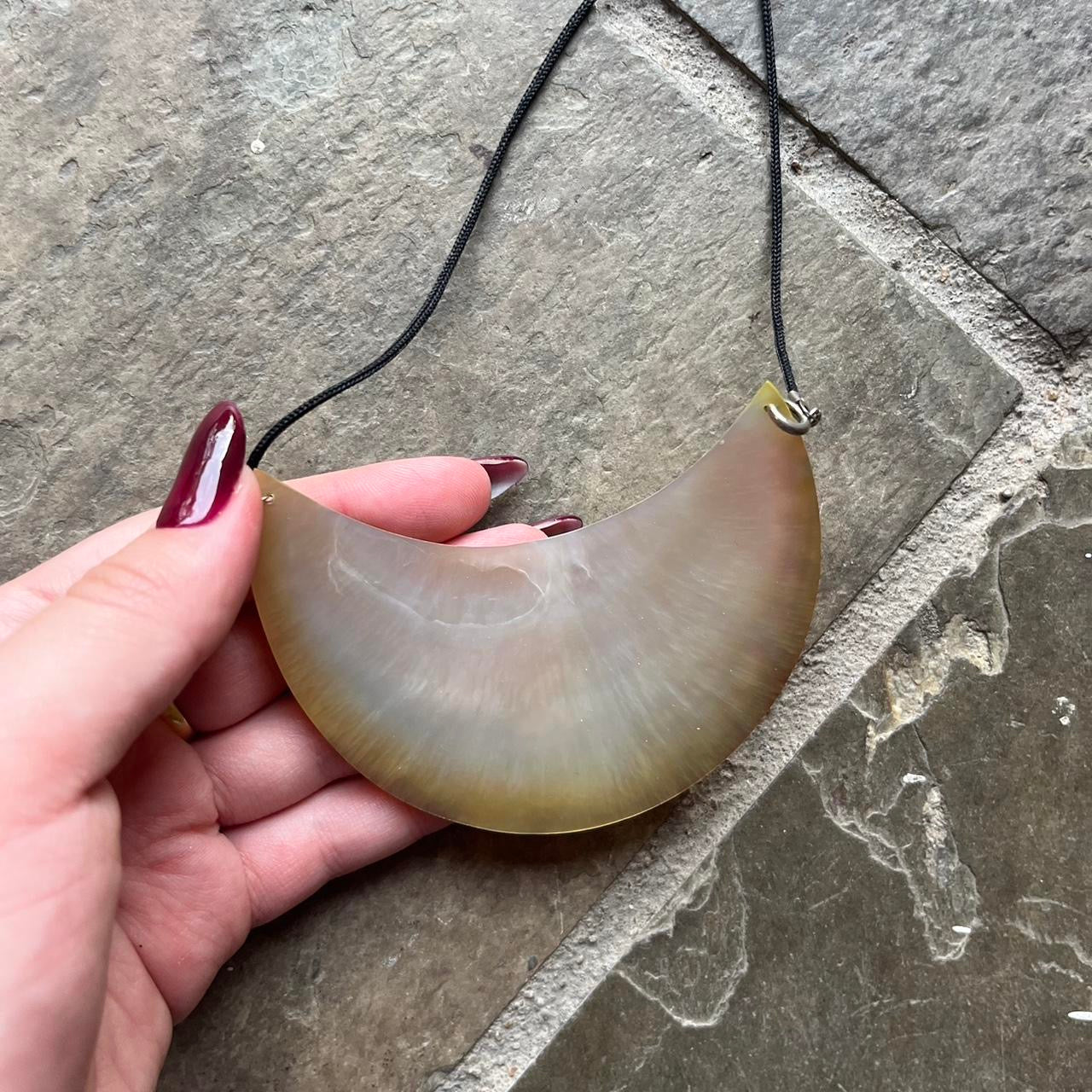 half crescent shell pendant on black thin rope chain